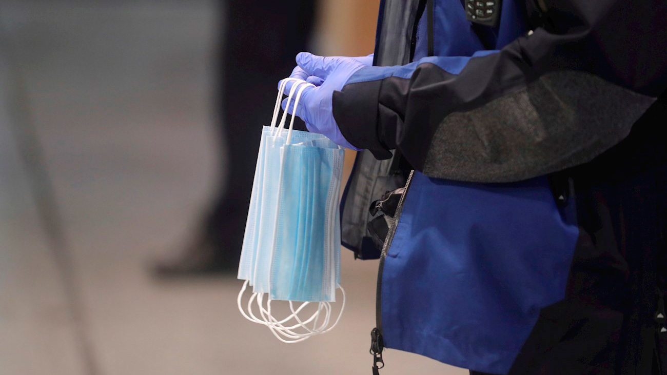 Un policía hace entrega a los usuarios del transporte público de mascarillas en la estación de Cercanías de Atocha (EFE)