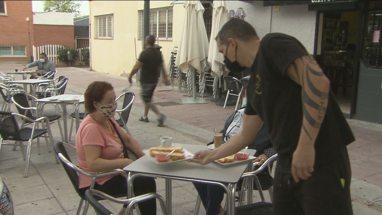 Un camarero y una clienta en un bar de Parla